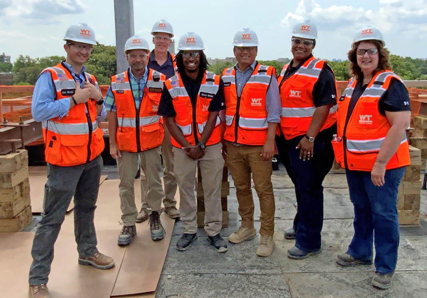 A group of educators participating in the Maryland Chamber Foundation's Teacher Externship Program alongside employees from their host company, Whiting-Turner, standing in a group at a construction site with safety equipment on.